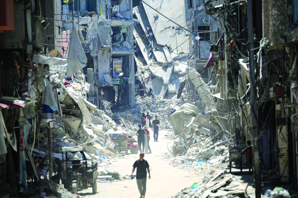 Palestinian men walk along a narrow street past destroyed buildings in Khan Yunis, in the southern Gaza Strip. — AFP 