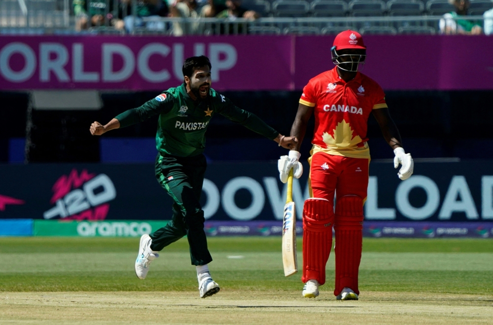 Pakistan's Mohammad Amir (L) celebrates the dismissal of Canada's Navneet Dhaliwal as Canada's Aaron Johnson looks on during the ICC men's Twenty20 World Cup 2024 group A cricket match between Pakistan and Canada at Nassau County International Cricket Stadium in East Meadow, New York on June 11, 2024.  (Photo by TIMOTHY A. CLARY / AFP)

