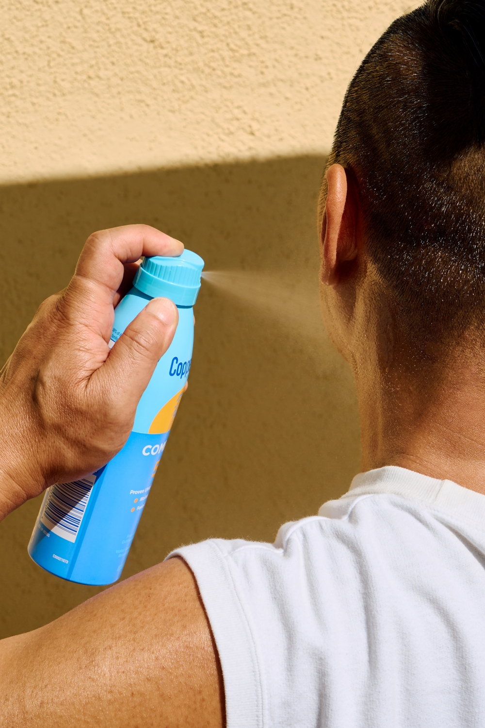 A man sprays his face with sunscreen in Los Angeles on June 1, 2024. (Joyce Lee/The New York Times)