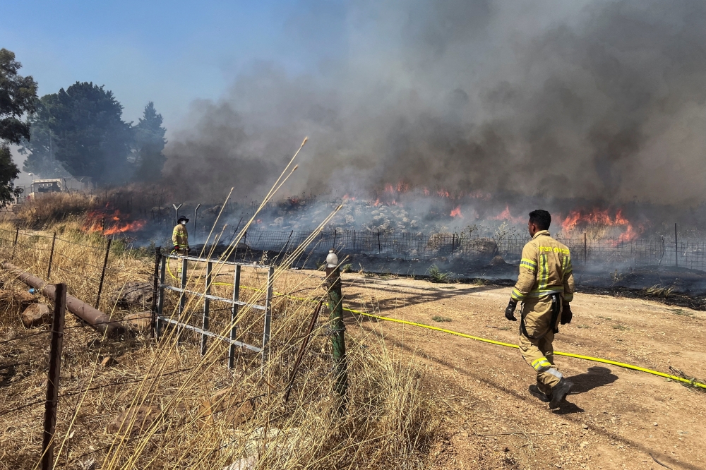 Israeli firefighters douse fire following rocket attacks from Lebanon on Thursday. — Reuters