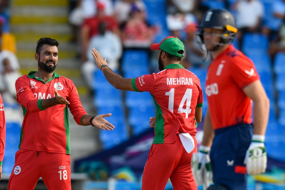 Bilal Khan (L) of Oman celebrates with Oman's Mehran Khan the dismissal of Phil Salt of England during the ICC men's Twenty20 World Cup 2024 group B cricket match