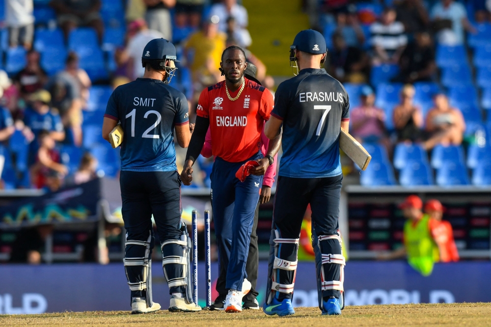 Namibia's JJ Smit (L) and Namibia's captain Gerhard Erasmus (R) congratulate England's Jofra Archer for winning their ICC men's Twenty20 World Cup 2024  - AFP
