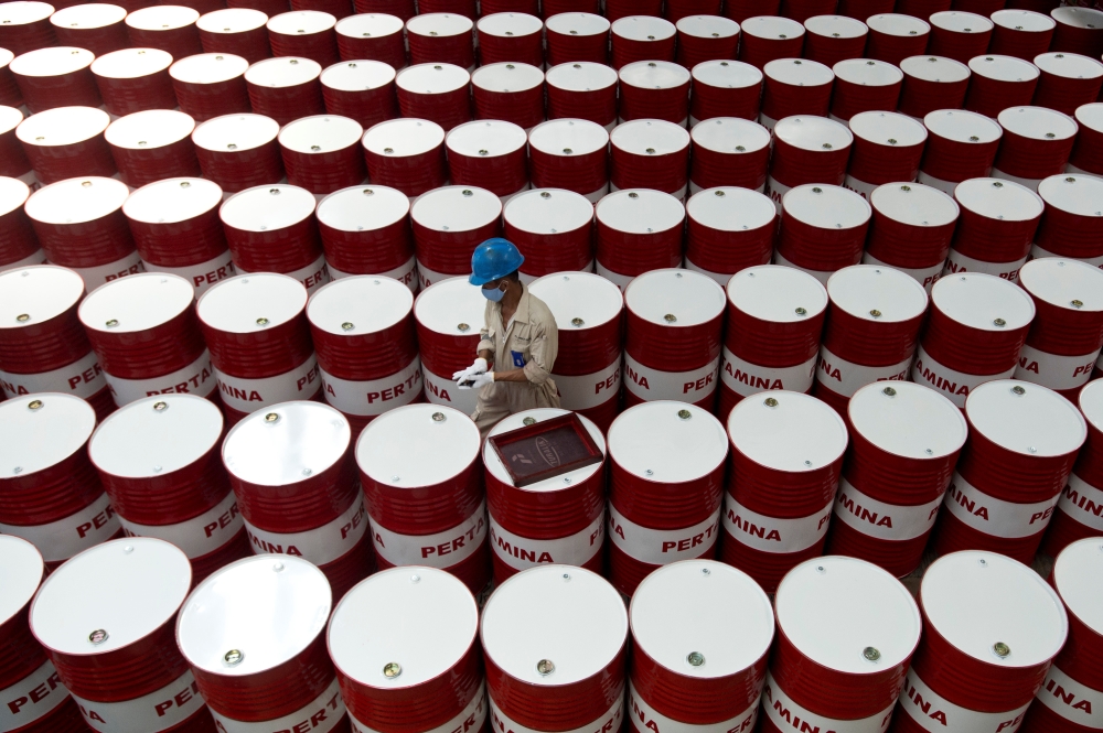 A worker prepares to label barrels of lubricant oil at the state oil company Pertamina's lubricant production facility in Cilacap, Central Java, Indonesia. — Reuters
