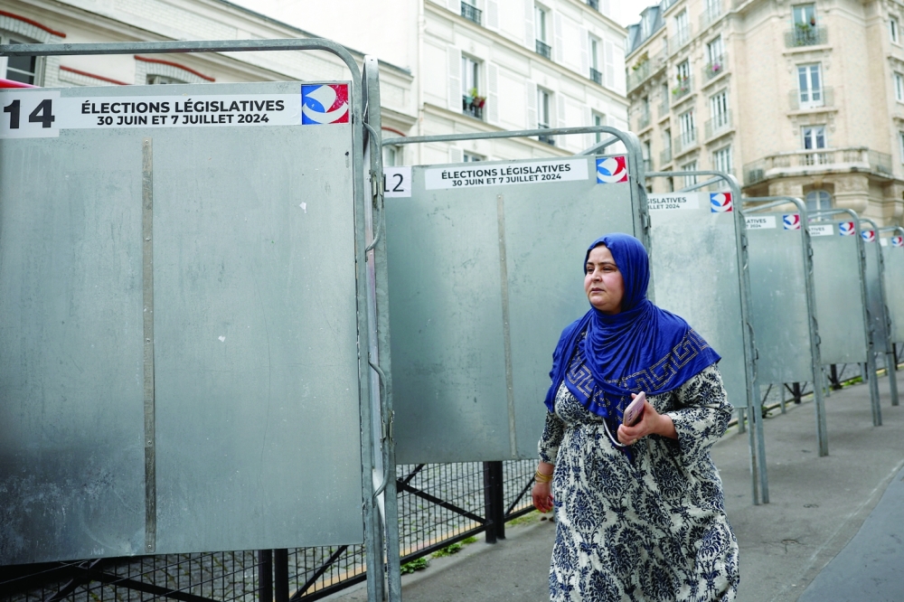 A woman passes by the election boards placed ahead of the June 30 and July 7 French parliamentary elections in Paris. - Reuters
