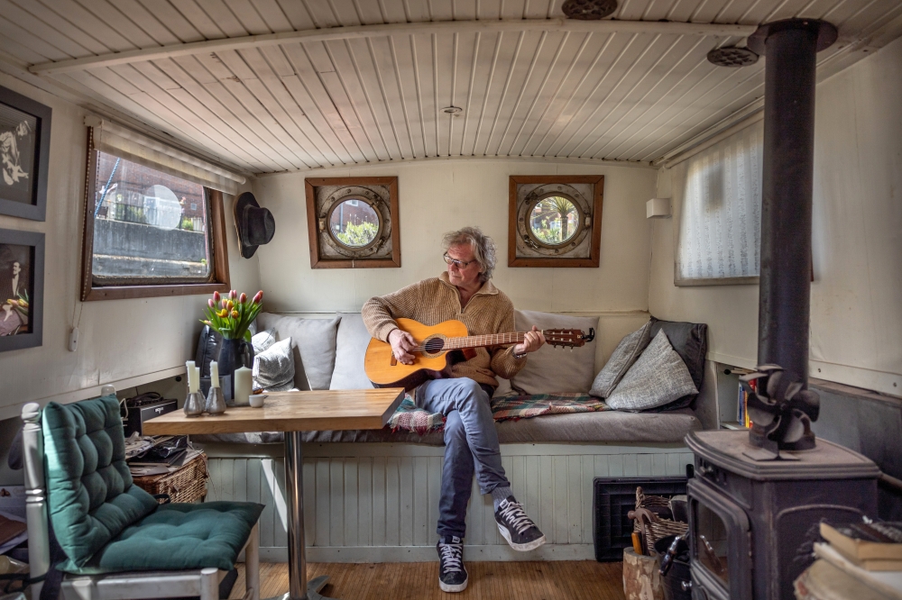 David Ros relaxes on his houseboat, which sits in the Grand Union Canal in Brentford, a London suburb. He bought the boat about six years ago and renovated it himself. (Jeremie Souteyrat/The New York Times)