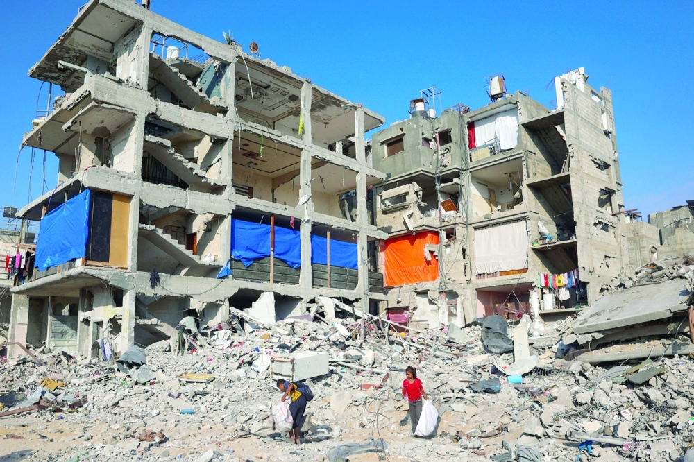 Palestinian children search for salvageable items in the debris of a destroyed building in Khan Yunis on Thursday. — AFP