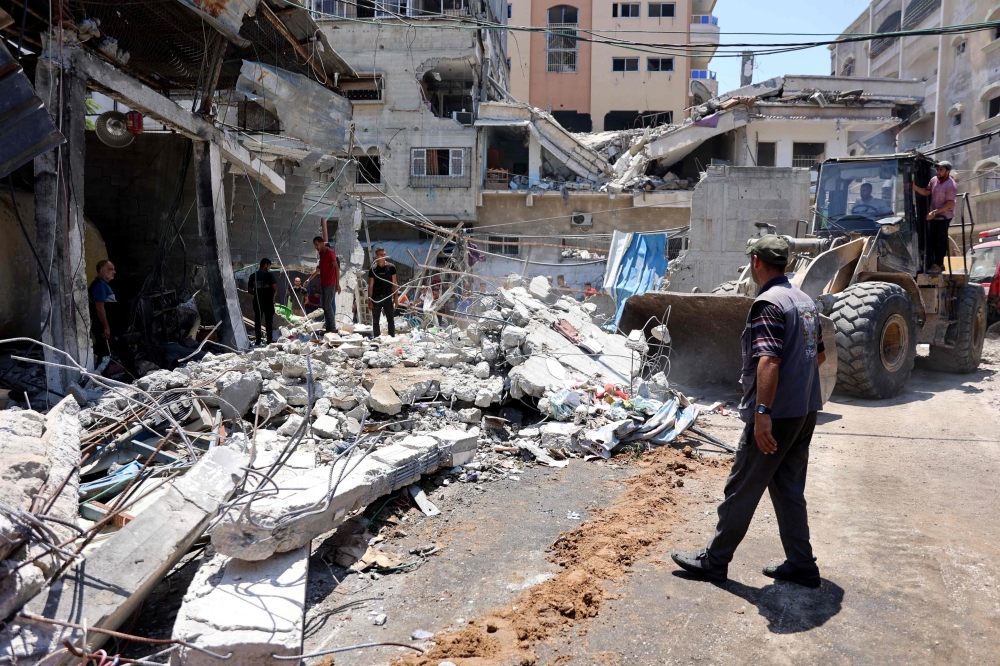 A digger is used to clear the debris following the Israeli military bombardment of the Gaza Municipality garage on al-Wahda Street