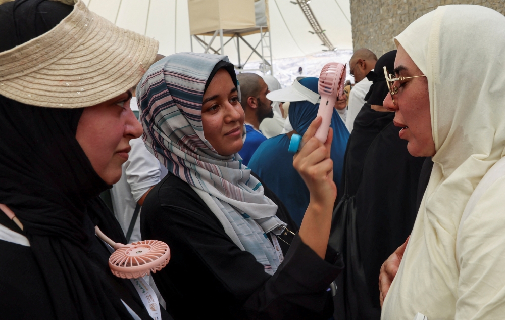 A woman fans the face of a pilgrim to cool down in Mina on Tuesday