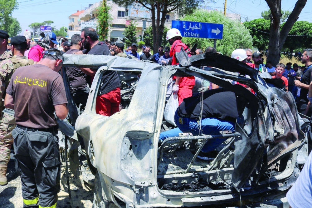 Emergency members and residents gather around the carcass of a car at the site of an Israeli strike in al-Khiyara town, in Lebanon. — AFP 