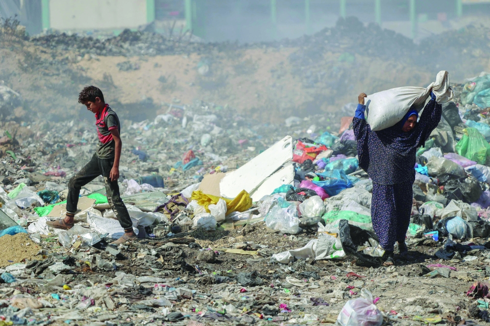 Palestinians search for salvageable items in a garbage dump which sprawls across what used to be the Firas market in Gaza. — AFP 