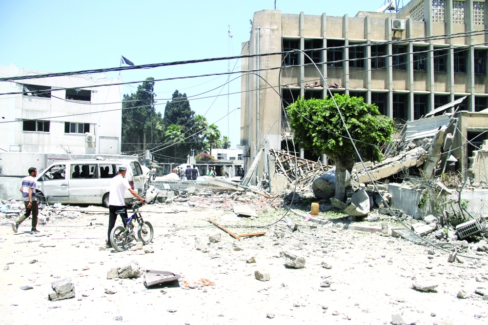 Palestinians search for casualties outside the headquarters of UNRWA following an Israeli strike, Gaza. — Reuters 
