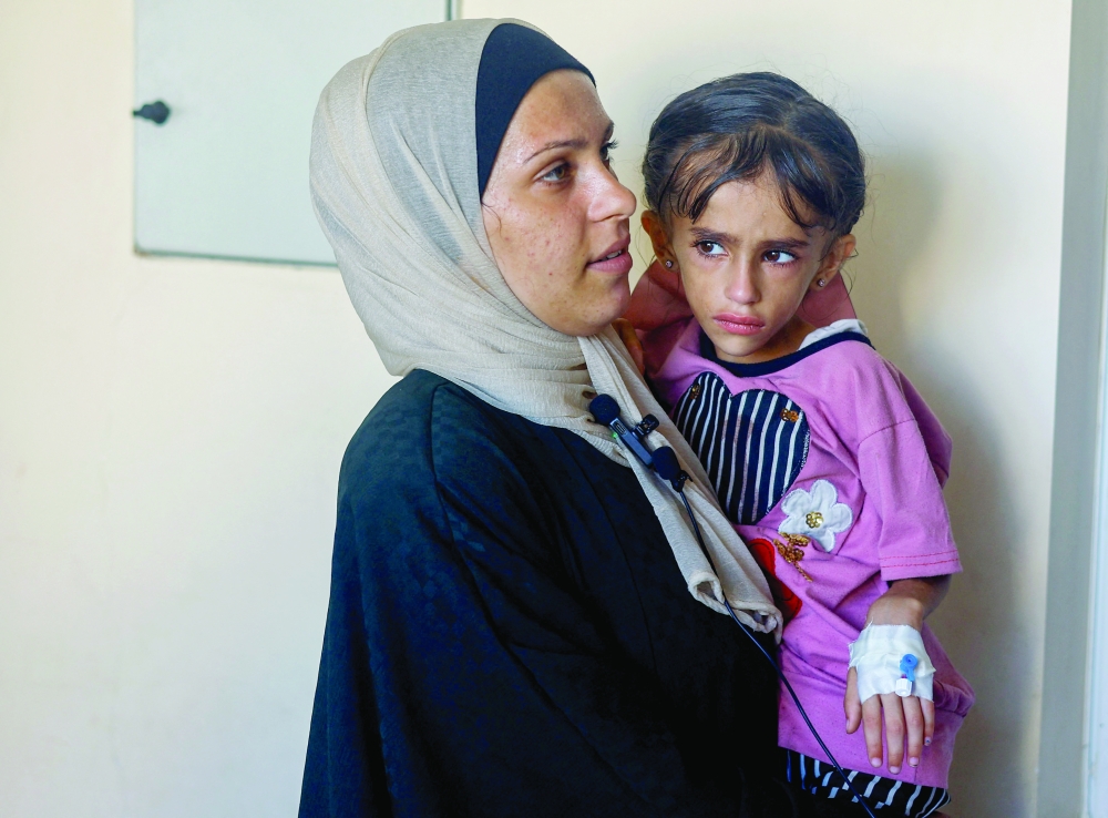 A Palestinian mother, Samira, holds her daughter Jori al Areer, who suffers from cancer and malnutrition as they wait to be transferred for treatment at Nasser hospital in Khan Younis on Monday. — Reuters