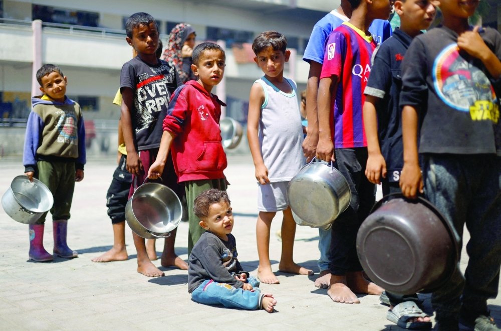 Palestinian children gather to receive food cooked by a charity kitchen, amid food scarcity, in Khan Younis. — Reuters 