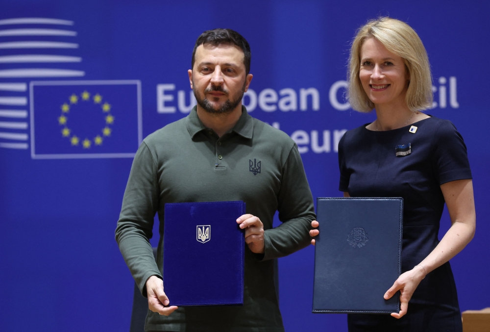 Ukraine's President Zelensky (L) and Estonia's Prime Minister Kaja Kallas pose with documents as they take part in a signature ceremony of security agreement with the EU during the European Council Summit at the EU headquarters in Brussels on June 27, 2024.  (Photo by Olivier HOSLET / POOL / AFP)