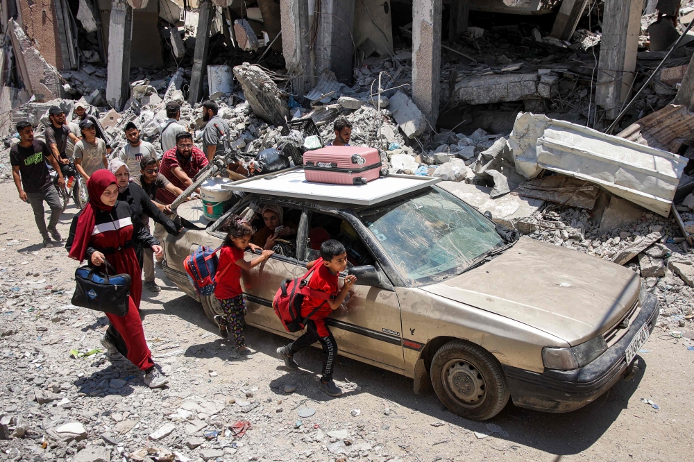 Children walk alongside a vehicle while evacuating with others from the Tuffah neighbourhood in the east of Gaza City heading towards areas in the west. - AFP

