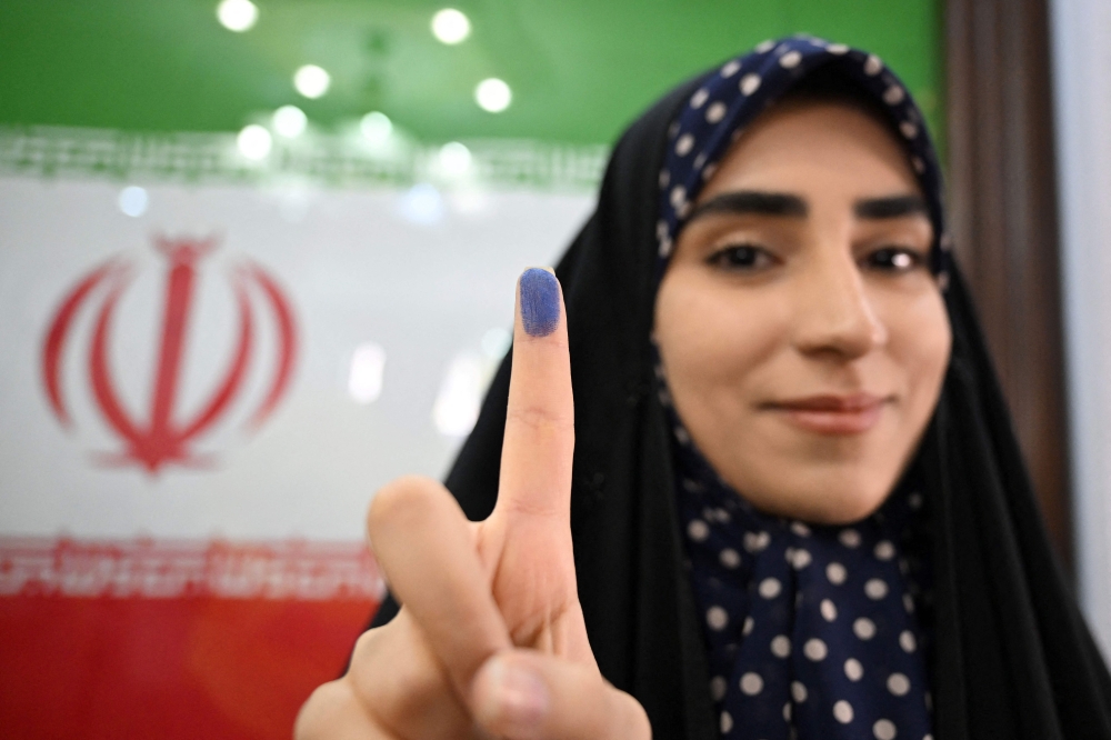 An Iranian woman shows her ink-stained finger after casting her vote during presidential election at the Iranian Consulate in Damascus