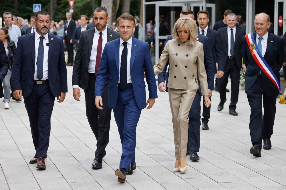 French President Emmanuel Macron (C) and his wife Brigitte Macron (C,R) leave the polling station  in Le Touquet, northern France. — AFP 