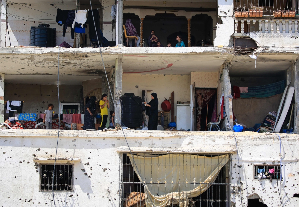 Palestinians families return to their badly damaged homes in an apartment block hit during previous Israeli bombardment, in the city of Khan Yunis. — AFP 