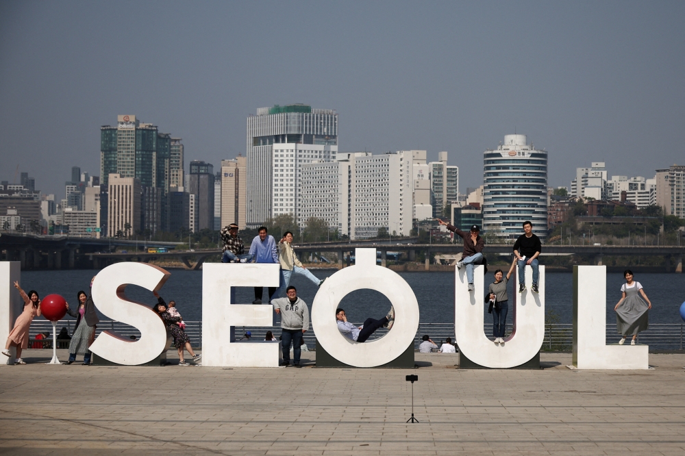 People pose for photographs on a sunny spring day at a Han river park in Seoul, South Korea. — Reuters