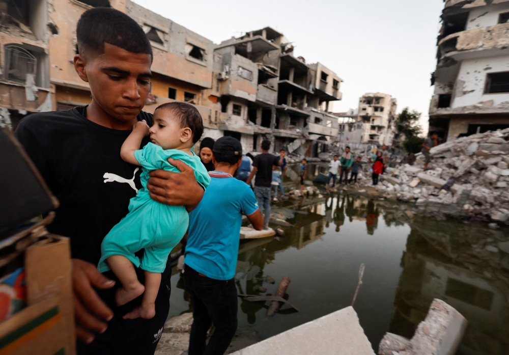 People stand near buildings destroyed in an Israeli strike, in Khan Younis on Monday. — Reuters