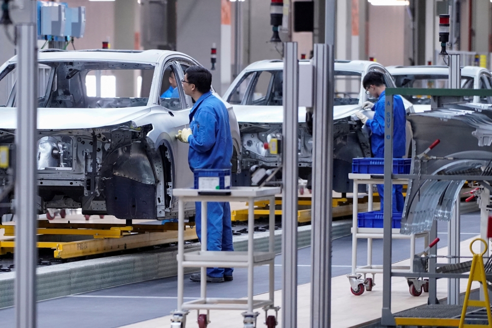 Employees work on assembly line during a construction completion event of SAIC Volkswagen MEB electric vehicle plant in Shanghai, China. — Reuters