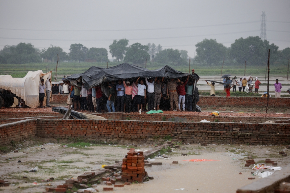 People take cover from the rain in the northern state of Uttar Pradesh, India. — Reuters 