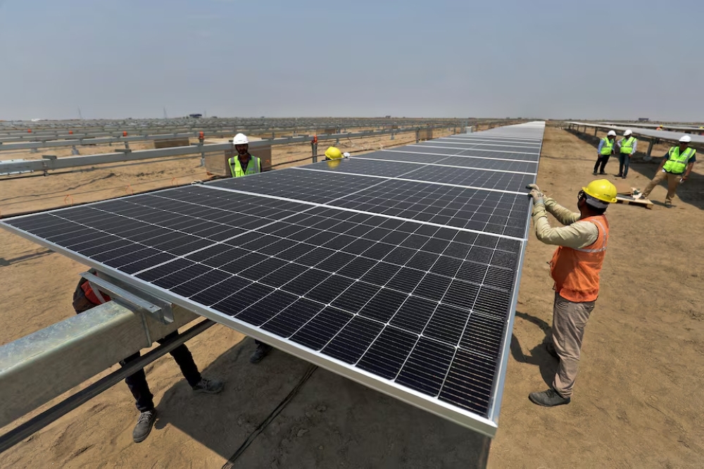 Workers install solar panels at the Khavda Renewable Energy Park of Adani Green Energy Ltd (AGEL) in Khavda, India. — Reuters