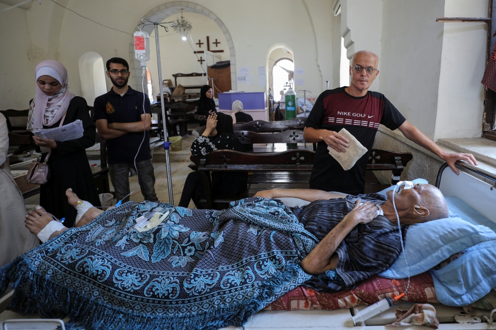 A Palestinian patient lies on a bed at the Baptist Church which was turned into a clinic as the wounded crowed the hospitals in Gaza City. - Reuters
