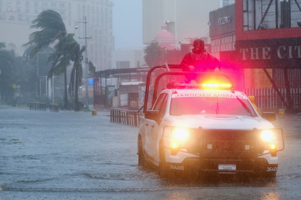 Members of the National Guard patrol through a flooded street during heavy winds and rain caused by Hurricane Beryl
