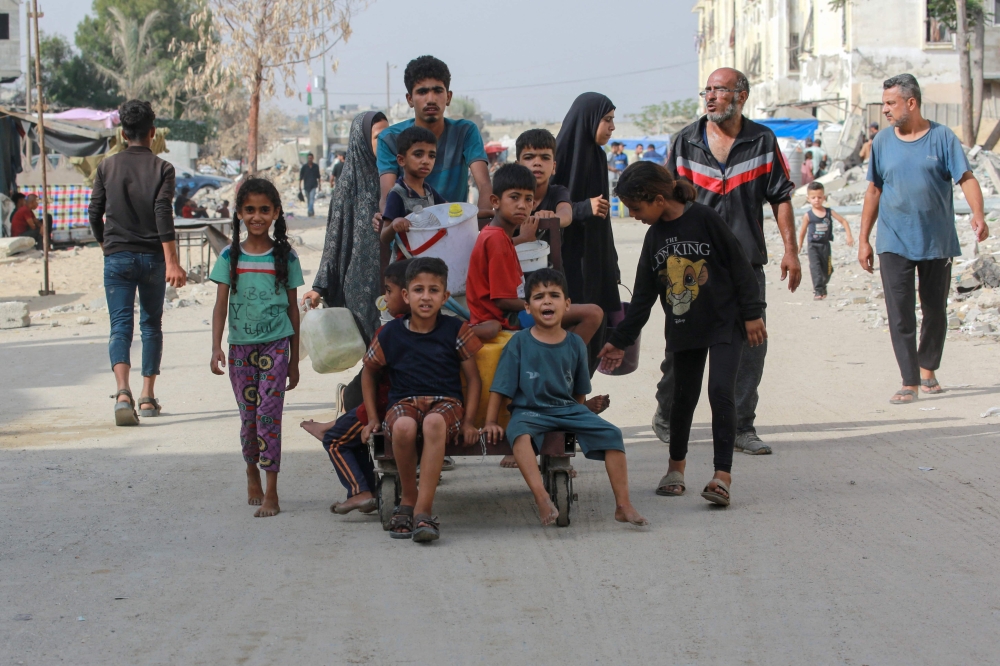 Palestinians walk through a heavly damaged residential district of the southern Gaza Strip city of Khan Yunis