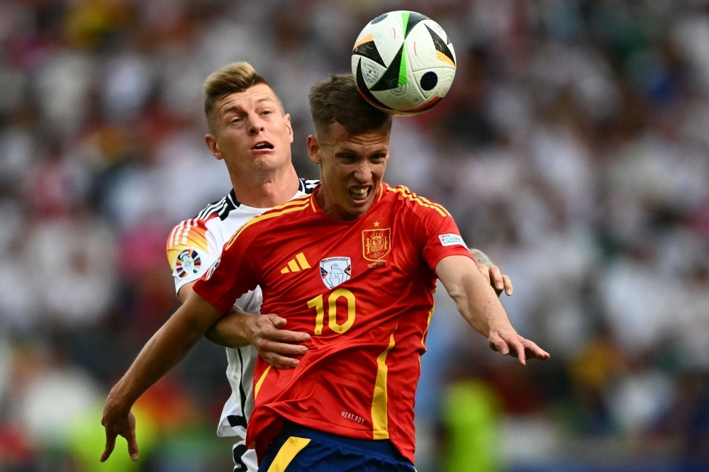 Spain's Daniel Olmo heads the ball against Germany's midfielder Toni Kroos during the UEFA Euro 2024 quarter-final football match between Spain and Germany at the Stuttgart Arena in Stuttgart on Friday