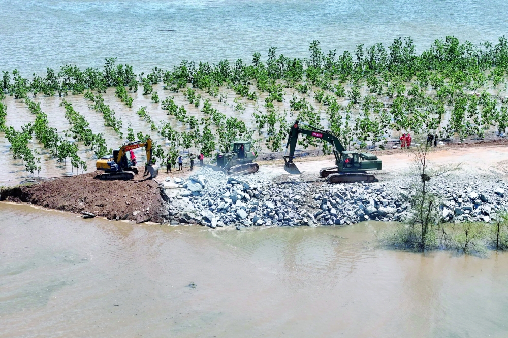 Workers attempt to repair a breach in the embankment on the shore of Dongting lake in Huarong county, in China's central Hunan province. -  AFP

