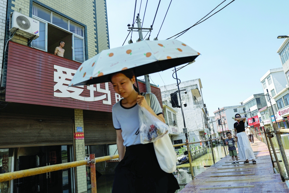 Residents cross a makeshift bridge after heavy rainfall and waters from the upstream Yangtze River flooded a town in Hukou county of Jiujiang, Jiangxi province. - Reuters
