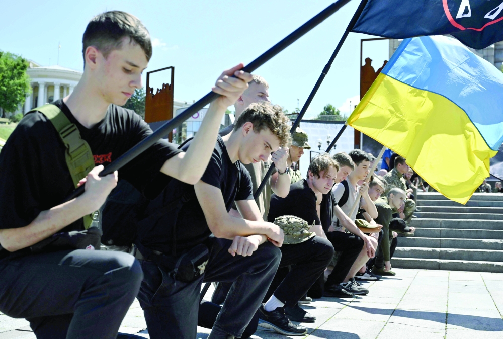 People kneel as servicemen of the Ukrainian Honor Guard carry out the coffin, during the farewell ceremony in Kyiv. — AFP 
