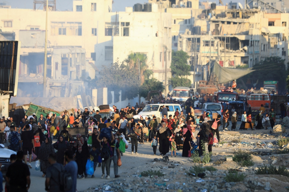 Palestinians flee and carry their belongings amid Israeli strikes, in Gaza City. — Reuters 