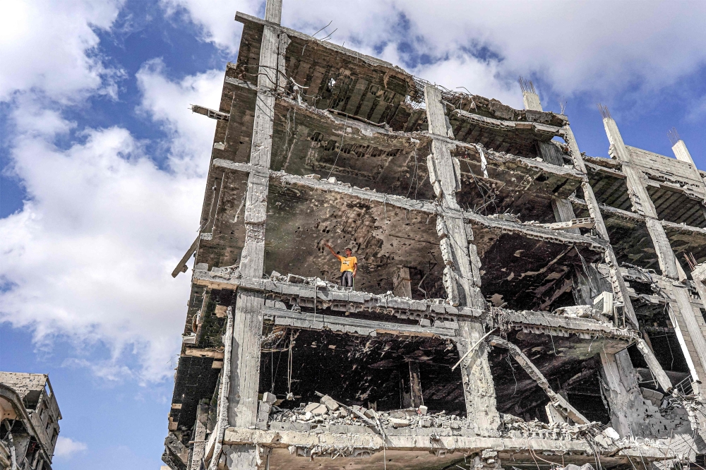 A man stands in one of the upper stories of a destroyed building in Khan Yunis. — AFP 