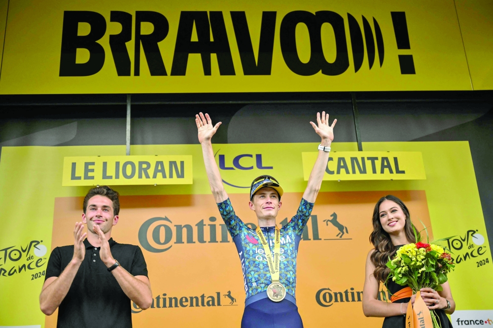 Jonas Vingegaard (C) celebrates on the podium  