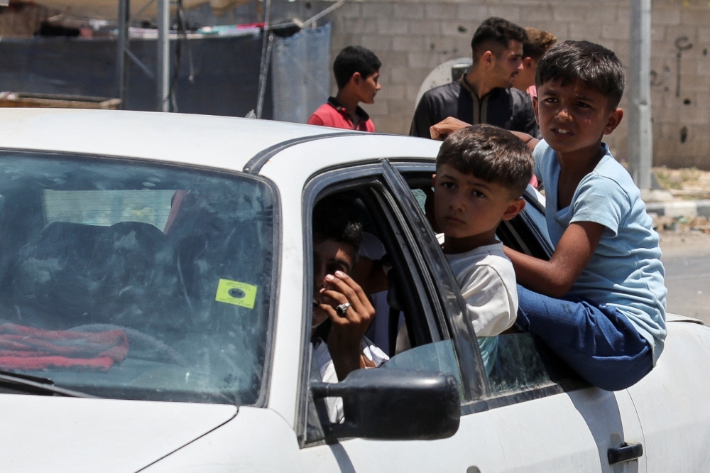 Displaced Palestinian children, who fled north Gaza after they were ordered by Israeli army to move southward, amid Israel-Hamas conflict, travel in a car as they arrive in Nuseirat in the central Gaza Strip. - Reuters