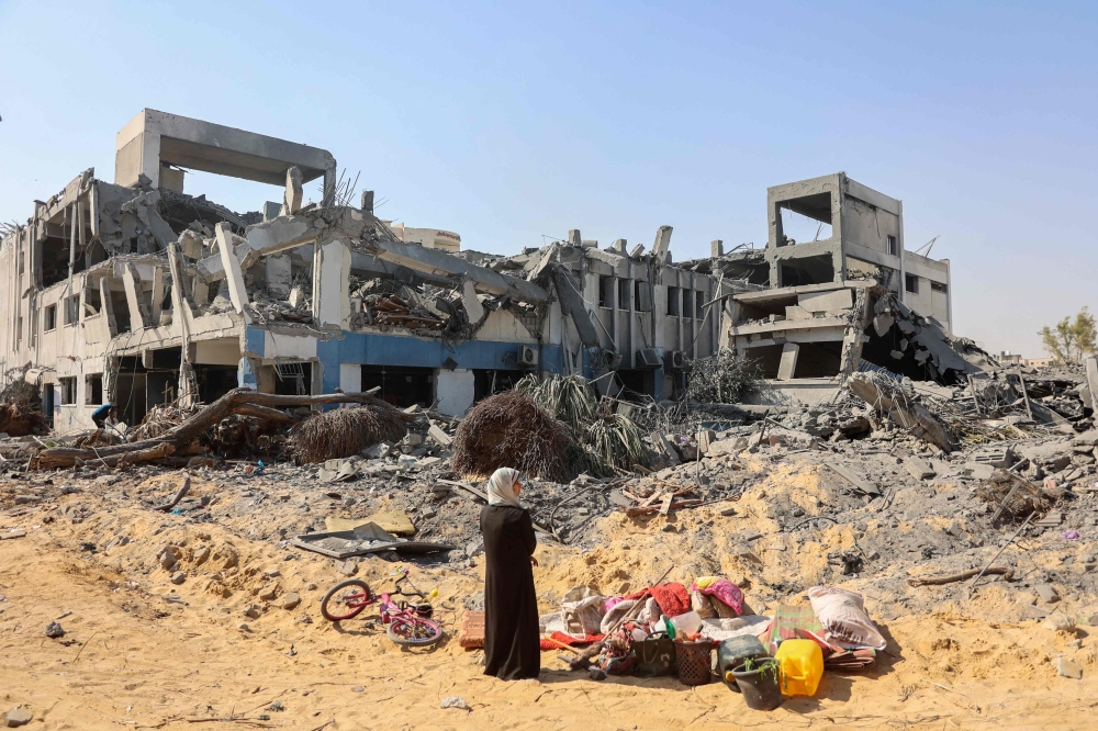 A woman looks around as she salvages items at the damaged UN Relief and Works Agency for Palestine Refugees (UNRWA) building complex 