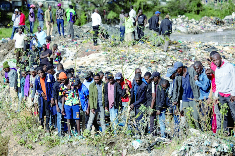 Onlookers gather at the dumpsite where six bodies were found in the landfill in Mukuru slum, Nairobi. — AFP