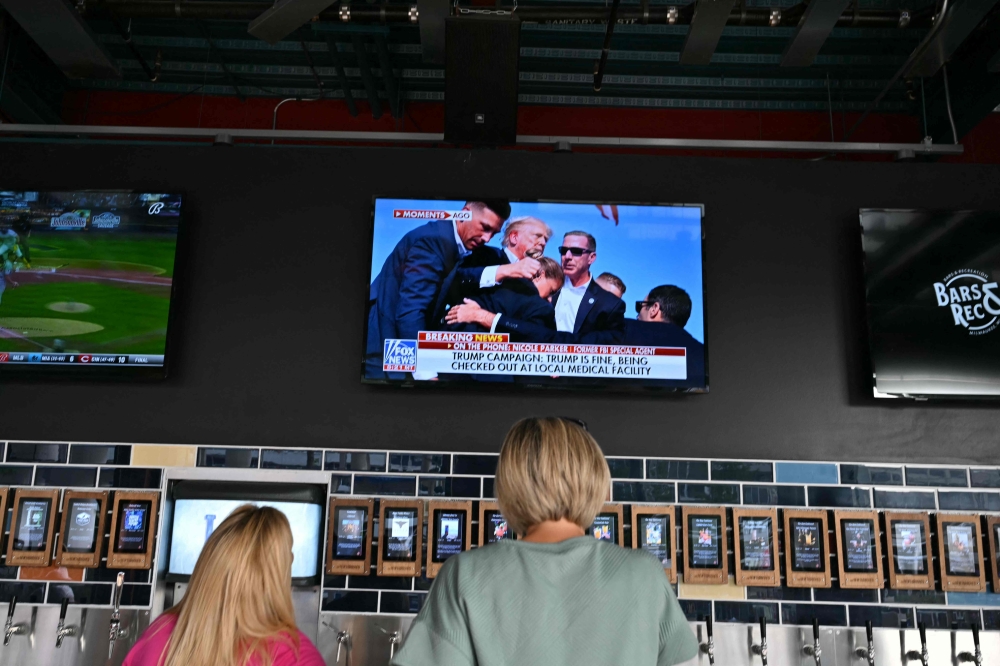 People inside the Fiserv Forum, watch the news on television after hearing that Donald Trump was evacuated from the stage of his rally in Pennsylvania after what sounded like shots rang out in Milwaukee, Wisconsin. — Reuters