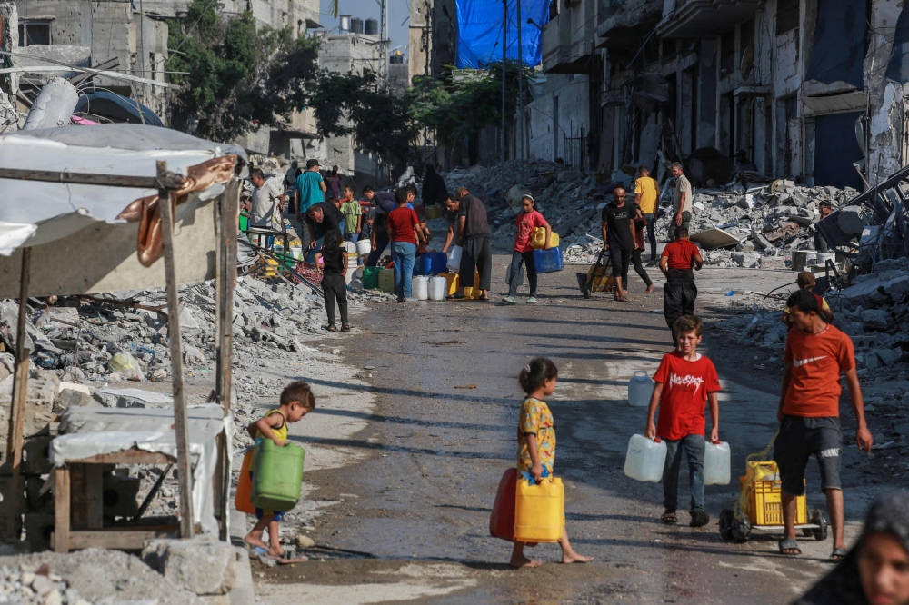 Palestinians queue to fill containers with water in Khan Yunis city. — AFP