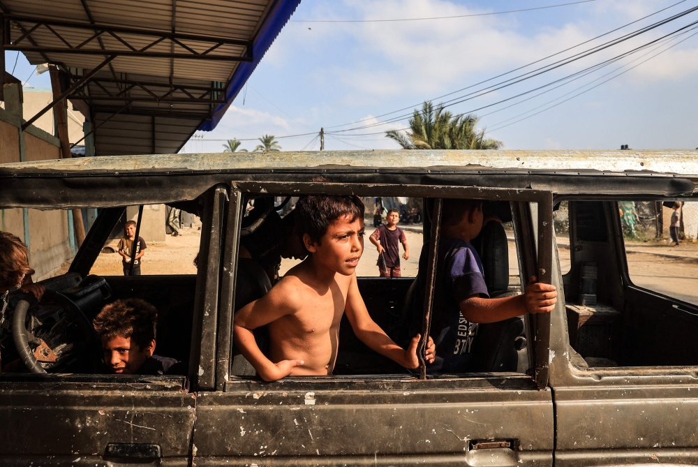  Internally displaced children play in a burnt out vehicle in the city of Deir al-Balah, in the central Gaza Strip. — AFP 