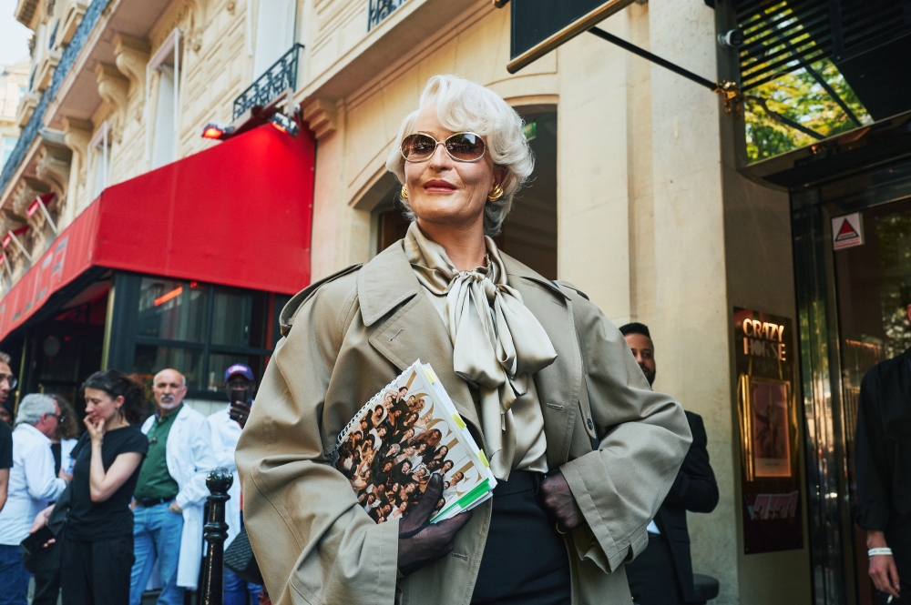 The devil herself: a person dressed as Miranda Priestly, the fictional fashion editor from the movie The Devil Wears Prada, replete with a mock issue of Vogue, outside the Balenciaga show during Couture Week in Paris, June 26, 2024. (Simbarashe Cha/The New York Times)