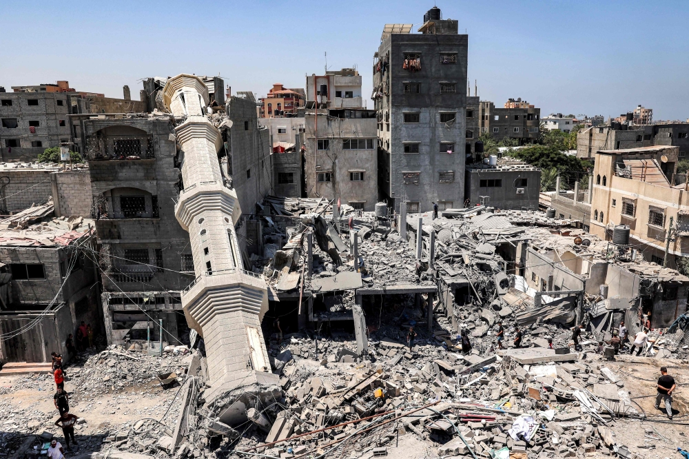 Men stand before the collapsed minaret of a mosque following Israeli bombardment in Nuseirat in the central Gaza Strip. — AFP 