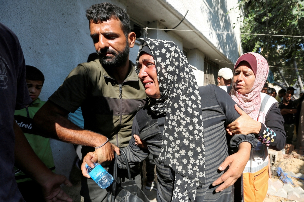 A relative of a Palestinian killed during the Israeli military offensive and buried earlier at Al Amal Hospital mourns as people prepare to transport and rebury them in a cemetery in Khan Younis in the southern Gaza Strip. - Reuters
