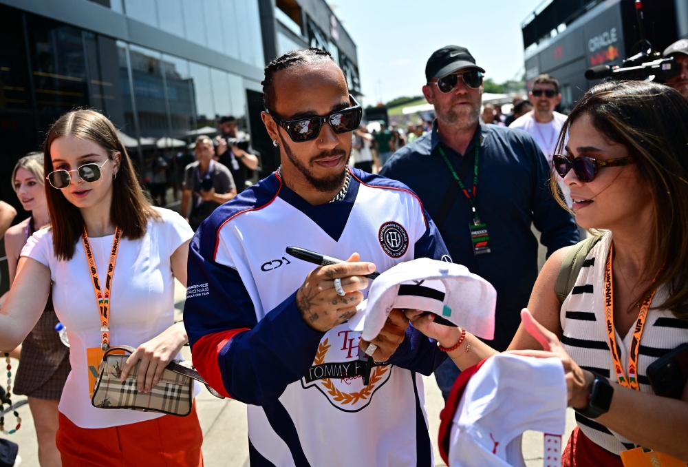 Mercedes' Lewis Hamilton signs autographs for fans. — Reuters