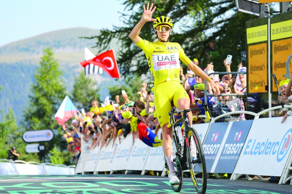 Tadej Pogacar celebrates crosses finish line. — AFp