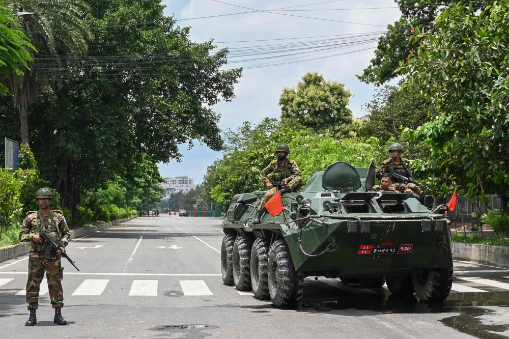 Bangladesh army personnel on armoured vehicles guard near the parliament house amid a curfew following clashes between police and protestors, in Dhaka on July 22, 2024.