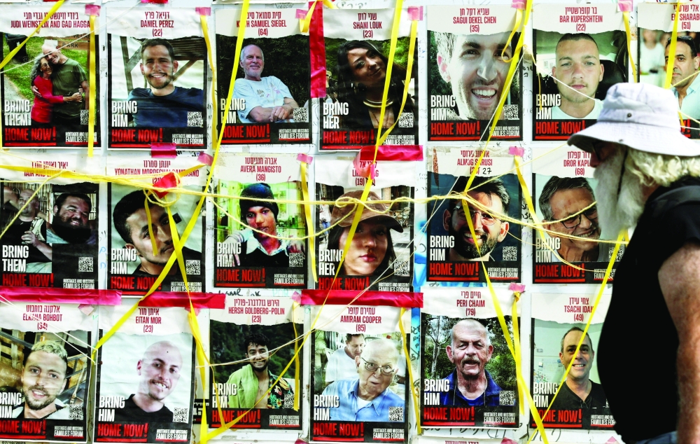 A person walks past posters of captives, in Tel Aviv. — Reuters 